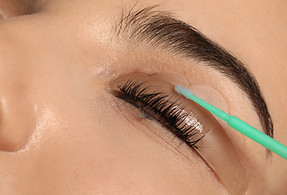 Young woman undergoing eyelash lamination, closeup_ Professional service